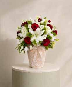 Luxury floral arrangement with red roses, white lilies, white lisianthus, and fresh greenery in an elegant decorative vase by Marino Flowers.