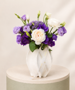 Elegant arrangement of peony roses and purple lisianthus in a luxury white decorative vase by Marino Flowers.