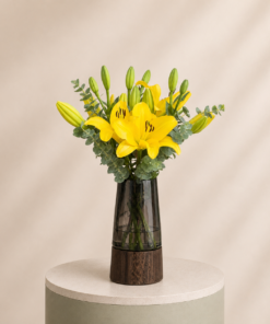 Elegant yellow lily arrangement with fresh eucalyptus in a luxury modern vase by Marino Flowers.