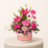 Luxury pink floral arrangement featuring pink lilies, roses, ranunculus, gerbera, and seasonal flowers in a decorative ceramic vase.