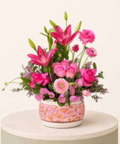 Luxury pink floral arrangement featuring pink lilies, roses, ranunculus, gerbera, and seasonal flowers in a decorative ceramic vase.