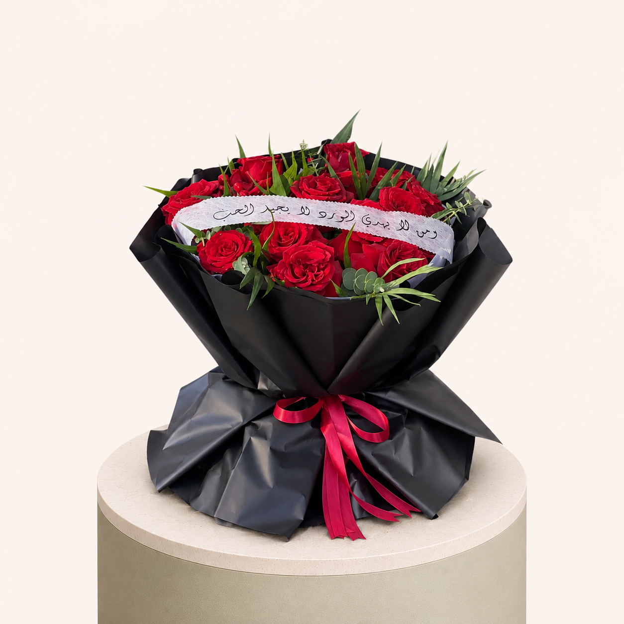 Fresh red roses with greenery wrapped in black paper and finished with a red ribbon by Marino Flowers.