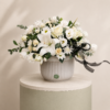 Luxury white floral arrangement with lilies, roses, chrysanthemums, lisianthus, and eucalyptus in an elegant ceramic vase.