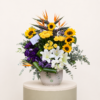 Luxury sunflower and lily arrangement with yellow roses, birds of paradise, and purple lisianthus in a ceramic vase.