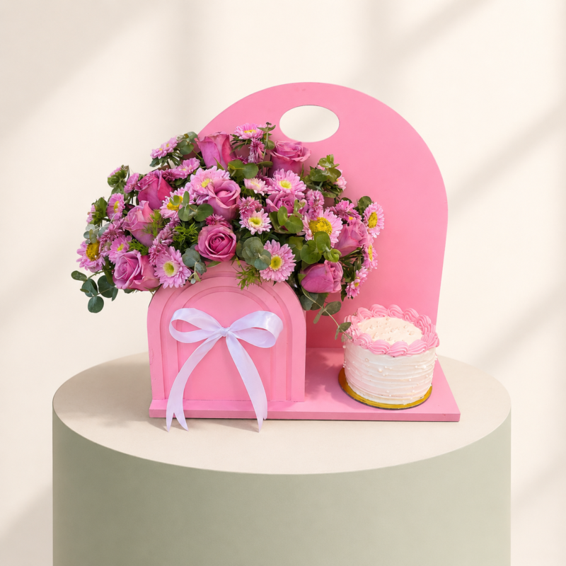 Pink floral arrangement with mini cake on a decorative pink stand by Marino Flowers