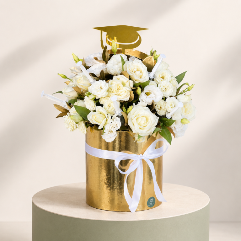 Golden graduation flower box with white roses, lisianthus, diploma picks, and graduation topper by Marino Flowers
