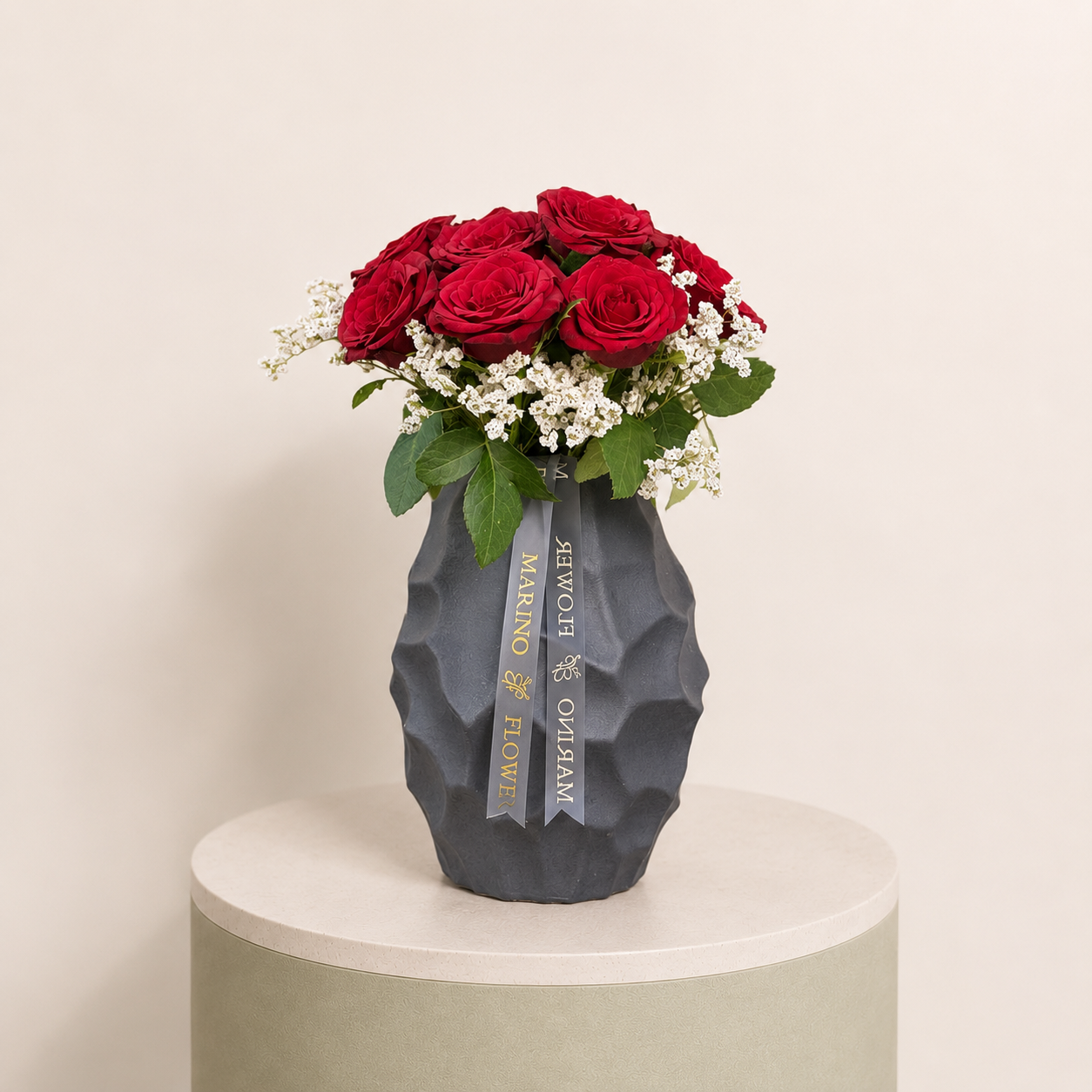 Red roses with delicate white filler flowers arranged in a textured black vase by Marino Flowers