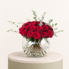 Luxury arrangement of premium red roses with eucalyptus in an elegant glass bowl vase by Marino Flowers.