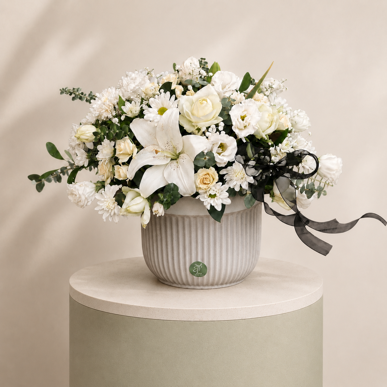 Luxury white floral arrangement with lilies, roses, chrysanthemums, lisianthus, and eucalyptus in an elegant ceramic vase.