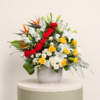 Luxury mixed flower arrangement with red roses, yellow roses, white lilies, birds of paradise, and eucalyptus in a ceramic vase.
