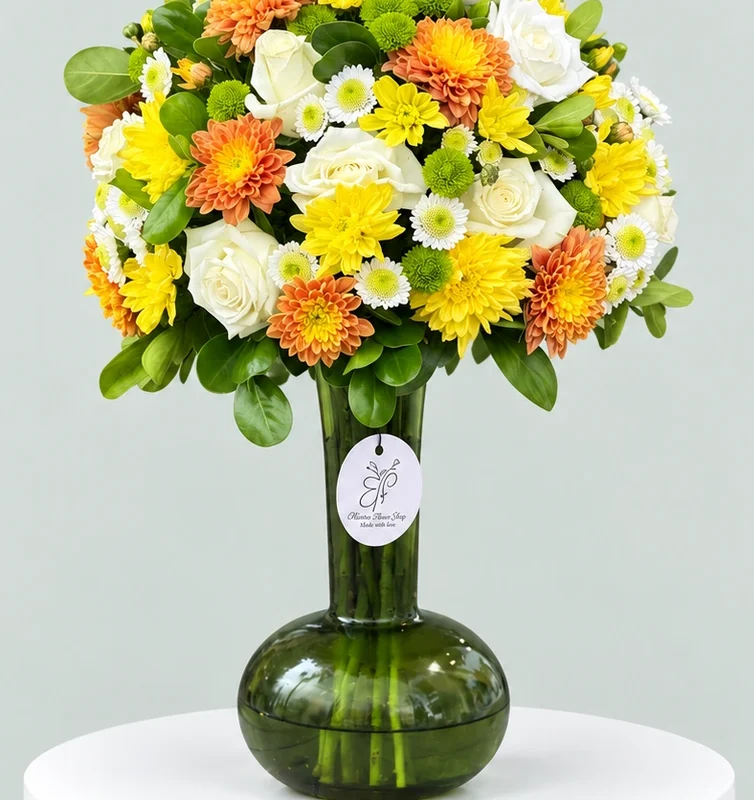 Golden Bloom Harmony – Luxury Mixed Flower Vase Medium mixed flower arrangement with white roses, yellow and orange chrysanthemums in a dark green glass vase.