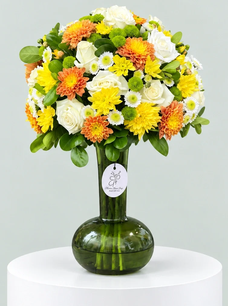 Golden Bloom Harmony – Luxury Mixed Flower Vase Medium mixed flower arrangement with white roses, yellow and orange chrysanthemums in a dark green glass vase.