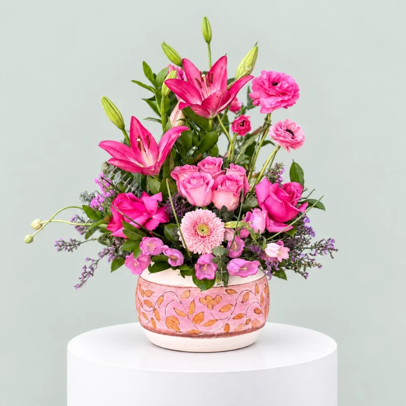 Luxury arrangement of deep red roses and silver-green eucalyptus in a clear round glass fishbowl vase by Marino Flowers.